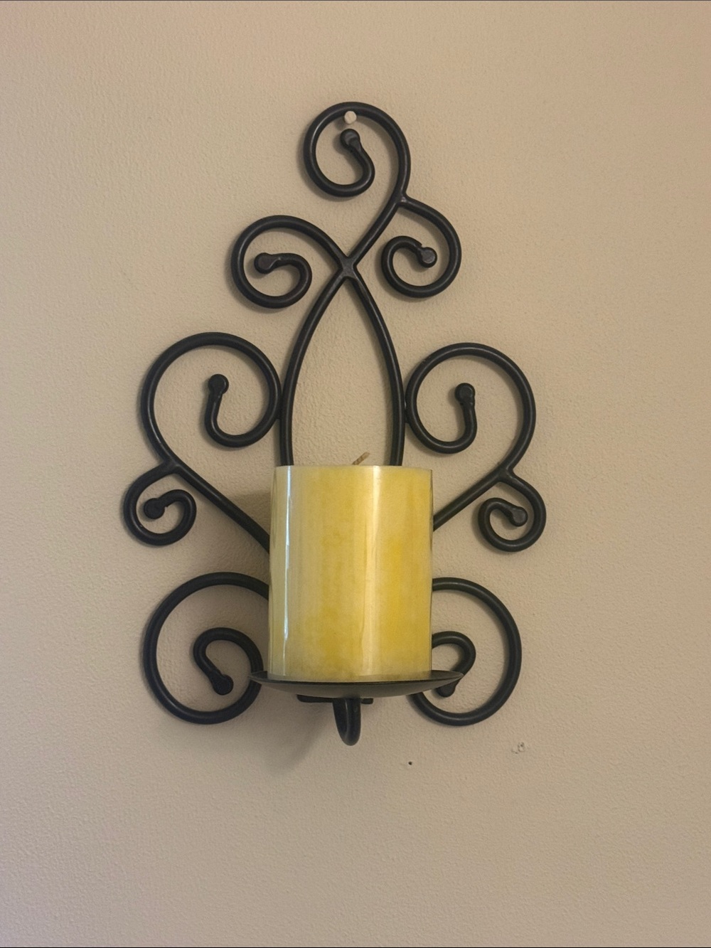 Black Swirl Metal Wall Sconce with Yellow Pillar Candle